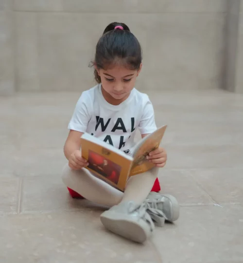 little girl reading a book and sitting on the floor